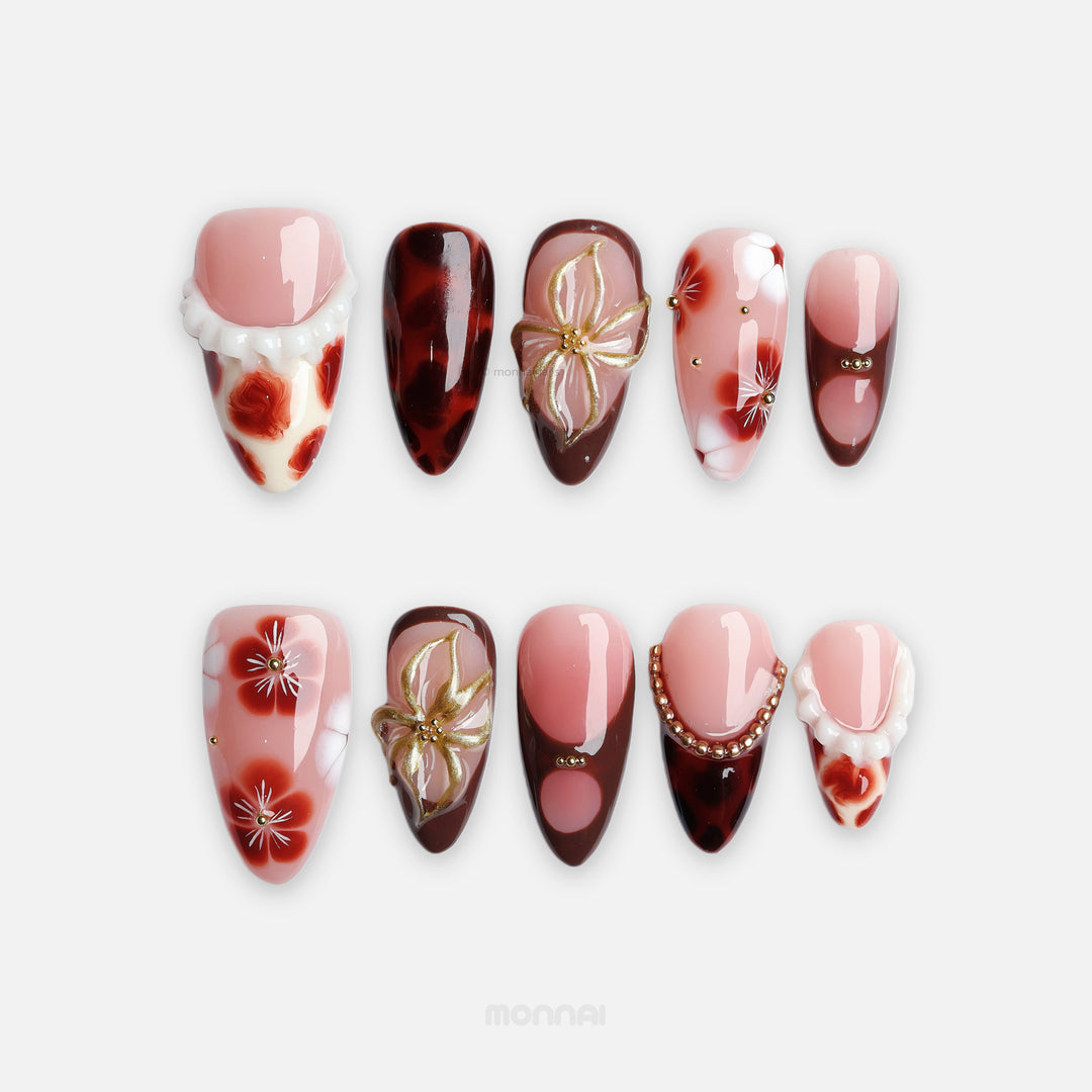 Twilight Shine press-on nails laid out in pink and nude tones with tortoiseshell accents, floral details, and gold touches