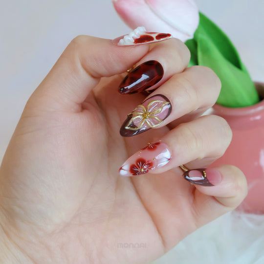Twilight Shine press-on nails shown on hand, with sculpted floral details, glossy tortoiseshell accents and gold touches.