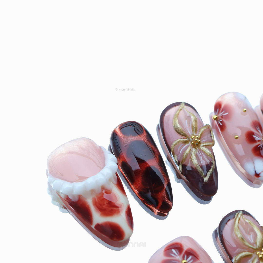 Twilight Shine press-on nails with sheer pink, warm nude, tortoiseshell accents, floral gold details, shown in close-up.