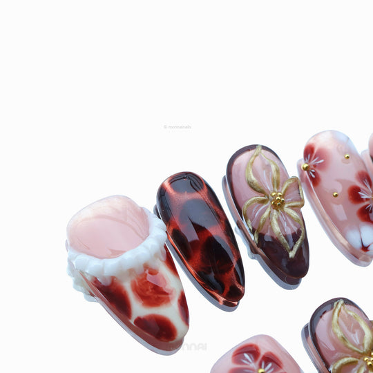 Twilight Shine press-on nails with sheer pink, warm nude, tortoiseshell accents, floral gold details, shown in close-up.