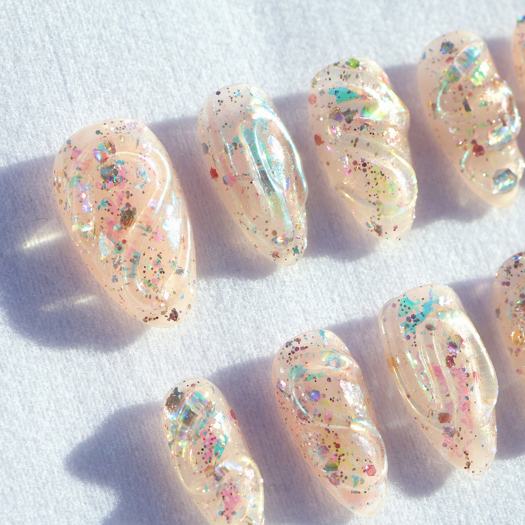 Twinkle press-on nails in close-up, sheer nude with iridescent glitter and glossy sculpted texture, glowy and delicate