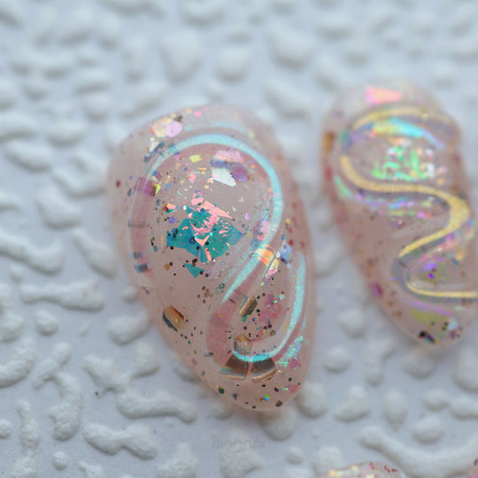 Twinkle press-on nails in close-up, sheer nude with iridescent glitter, glossy sculpted texture, and rainbow shimmer