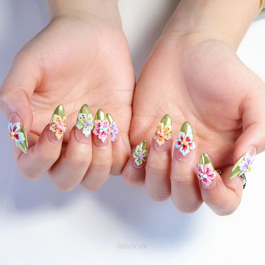 Vibrant Blossoms press-on nails worn on hands, nude base with olive green French tips and colorful 3D flowers.