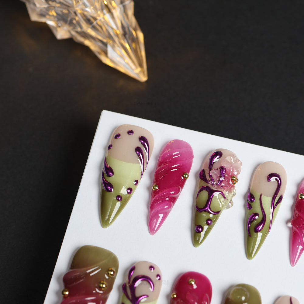 Vine press-on nails laid out, showing cool pink and olive Y2K swirls with metallic purple lines and gold studs.