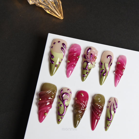 Vine press-on nails laid out in a Y2K style, with pink and olive swirls, metallic purple lines, and gold studs