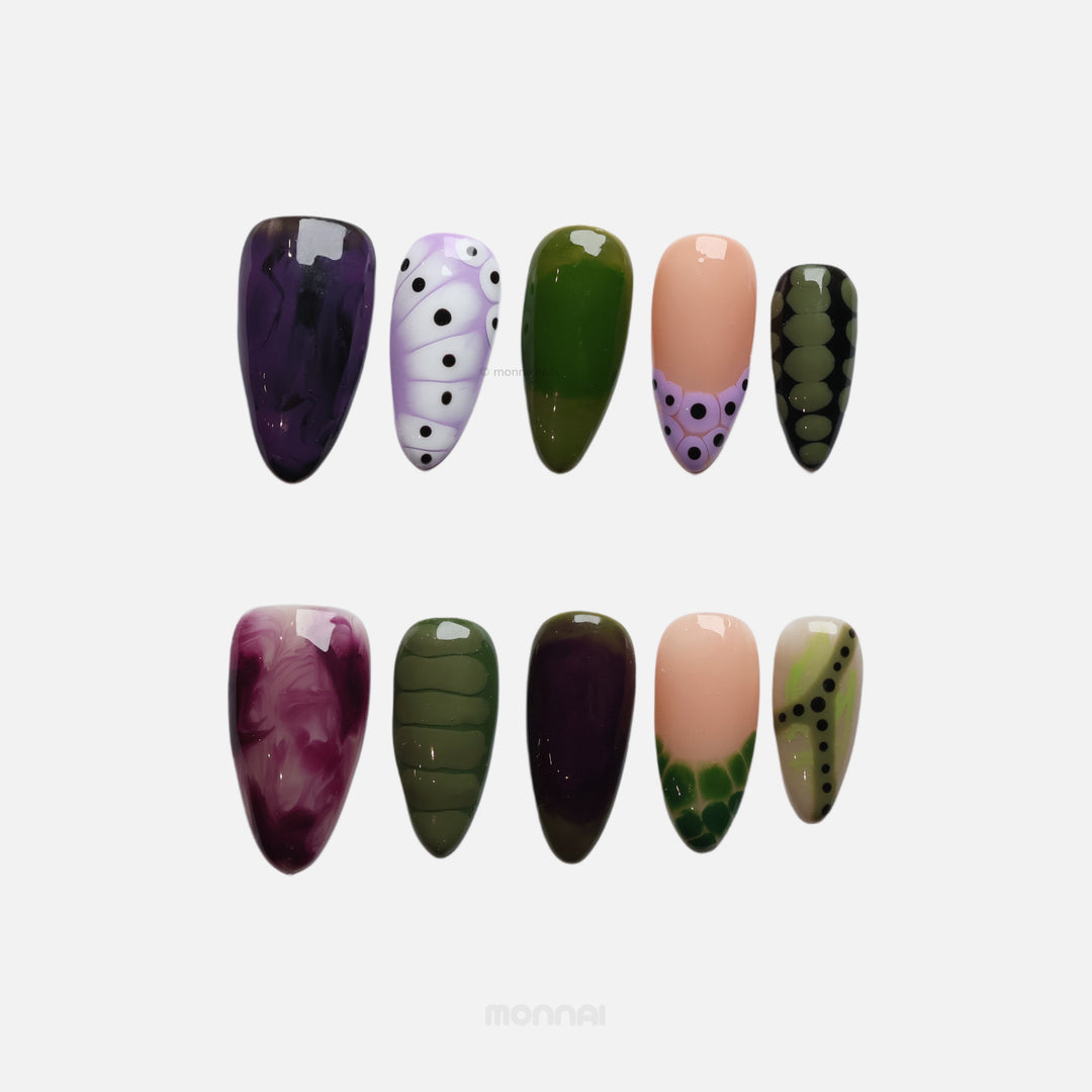 Violet Vines press-on nails with glossy moody purple, olive green, and nude designs, laid out in a set