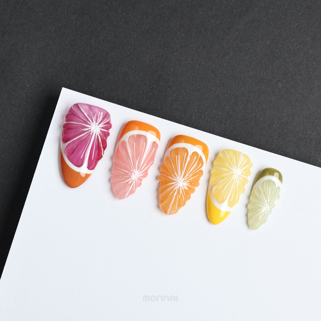 Vitamin C Crew press-on nails laid out with grapefruit, orange, lemon and lime slice designs