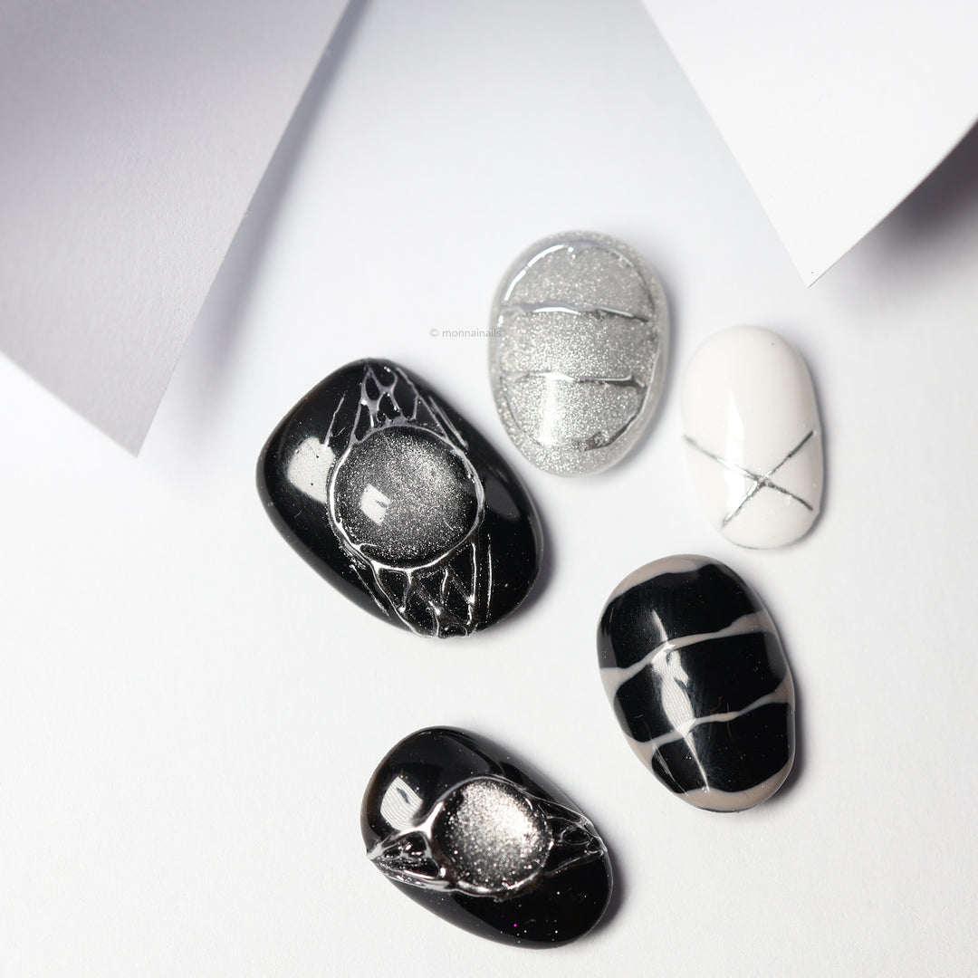 Void Spark press-on nails laid out in black, silver, and white with chrome accents and abstract linework
