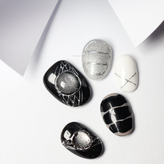 Void Spark press-on nails laid out in black, silver, and white with chrome accents and abstract linework