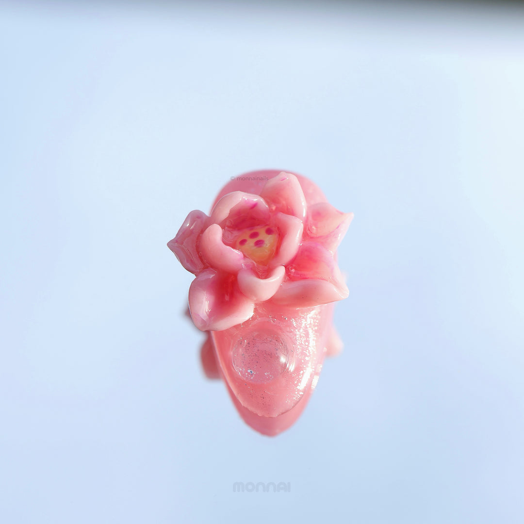 Water Lily Dream press-on nails in close-up, showing a glossy pink hand-painted floral design with sculpted water lily details.