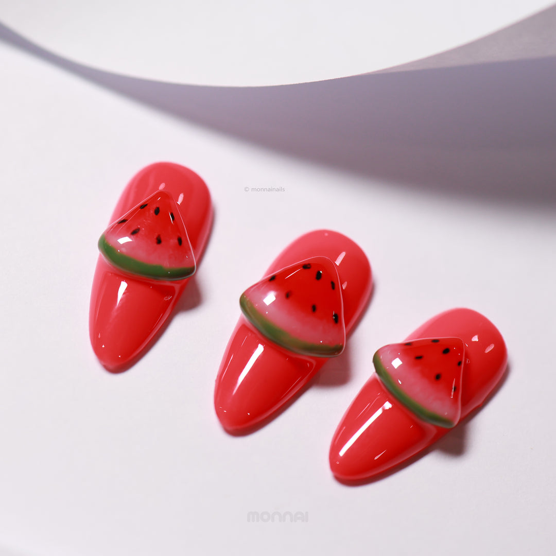 Watermelon Fun press-on nails laid out in close-up, with glossy red bases and hand-painted watermelon slice accents.