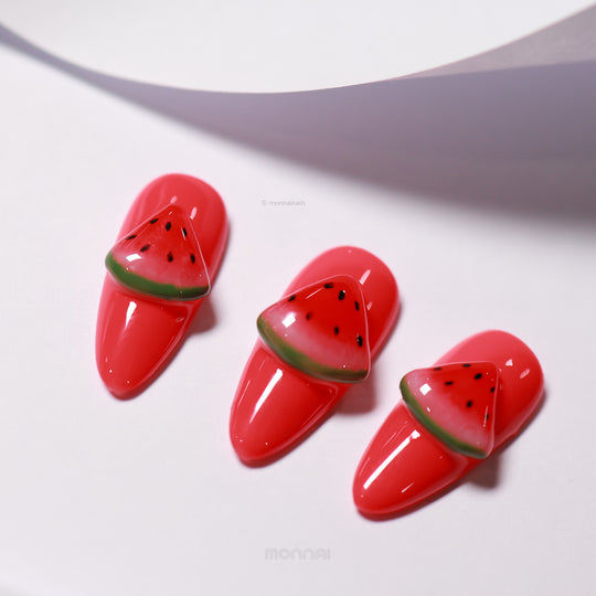 Watermelon Fun press-on nails laid out in close-up, with glossy red bases and hand-painted watermelon slice accents.