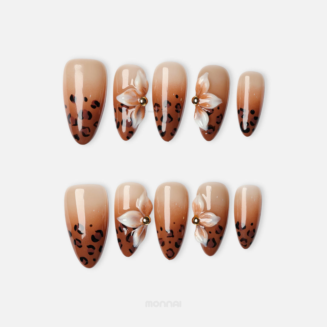 Wild Charm press-on nails with brown leopard print tips and white floral accents, shown in a laid-out set