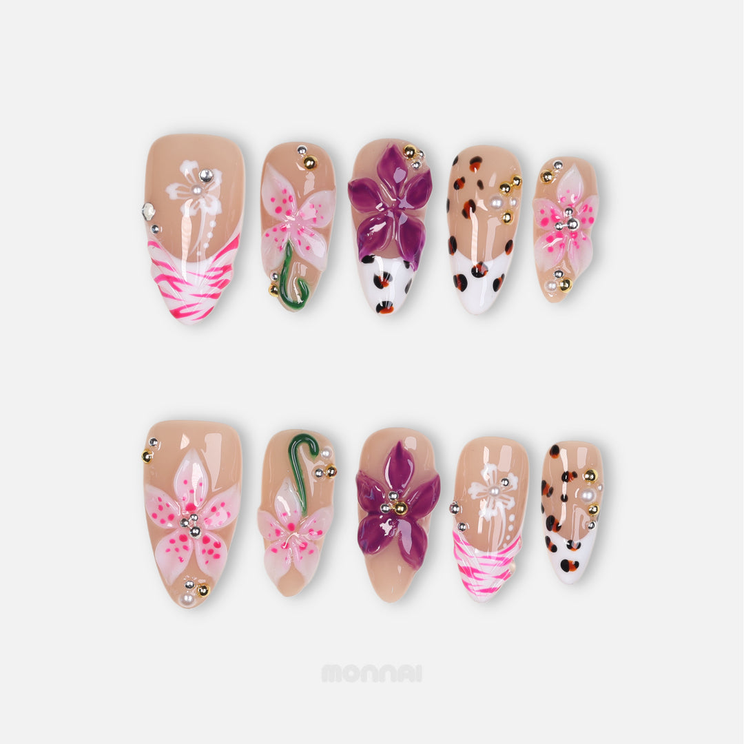 Wild Things press-on nails laid out, featuring pink and plum 3D flowers, leopard print, zebra stripes, and rhinestones.