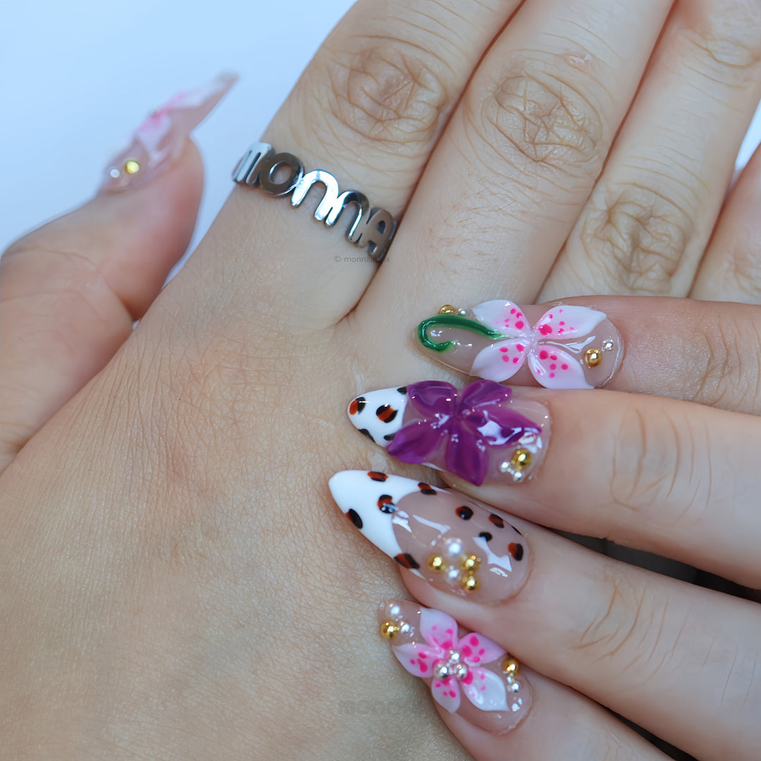 Wild Things press-on nails worn on hand with pink and plum 3D flowers, leopard-print details, and rhinestones