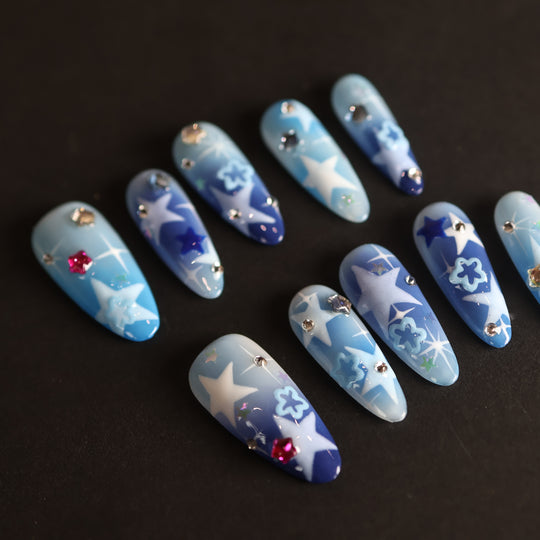 Wishing Jar press-on nails laid out with dreamy blue-to-navy star designs and scattered rhinestones