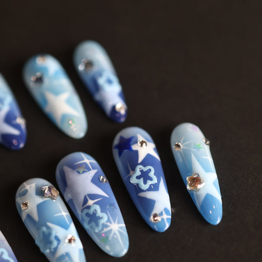 Wishing Jar press-on nails laid out with dreamy blue star designs, rhinestones, and glossy finish