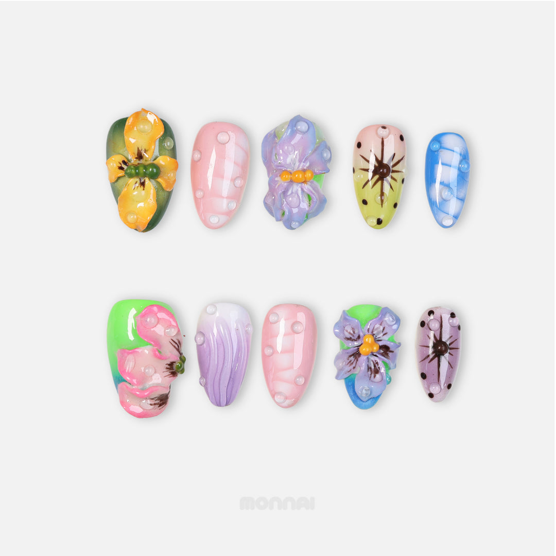 Wonderland press-on nails laid out with pastel mismatched 3D floral and water-drop details