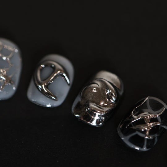 X-Edge press-on nails in a close-up, showing monochrome cybercore rebellion with liquid metal chrome lines and glossy black-and-white designs