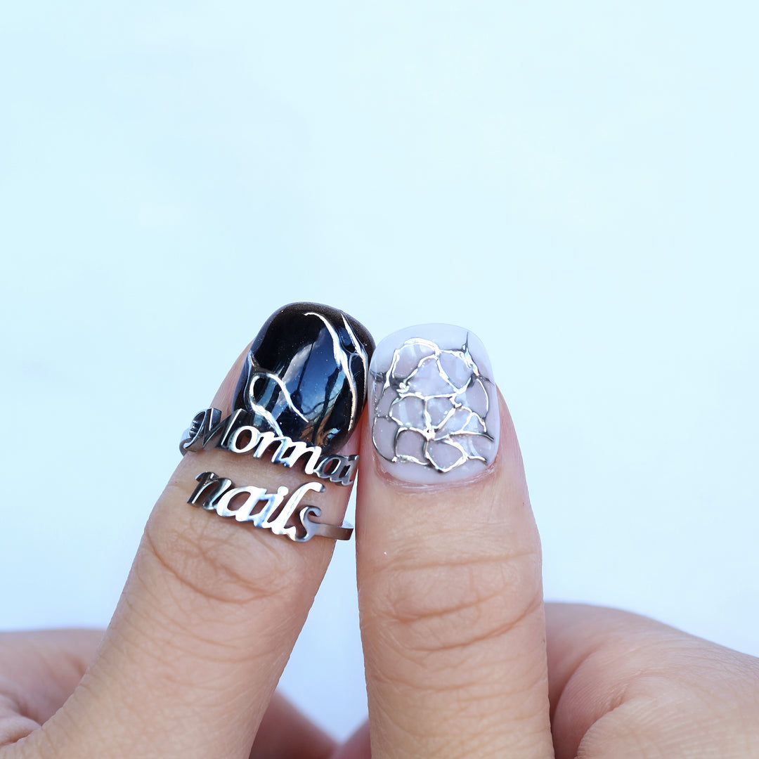 X-Edge press-on nails worn on fingers, black-and-white cybercore design with chrome crackle lines