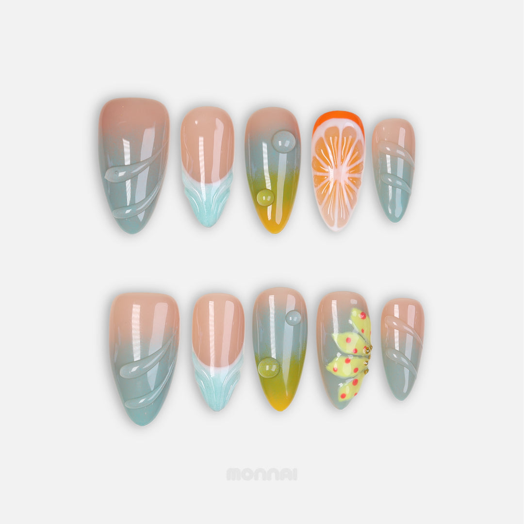 Zesty Summer press-on nails shown in close-up, with soft blue-green fades, citrus accents, and glossy raised gel details.