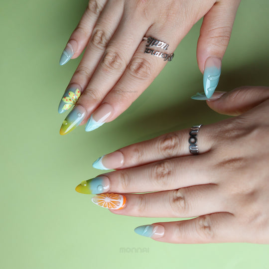 Zesty Summer press-on nails worn on hands, with blue-green fades, citrus details, and glossy water-drop accents.