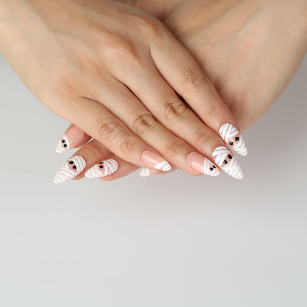 Peekaboo Mummy press-on nails on hands with white bandage stripes and black eyes