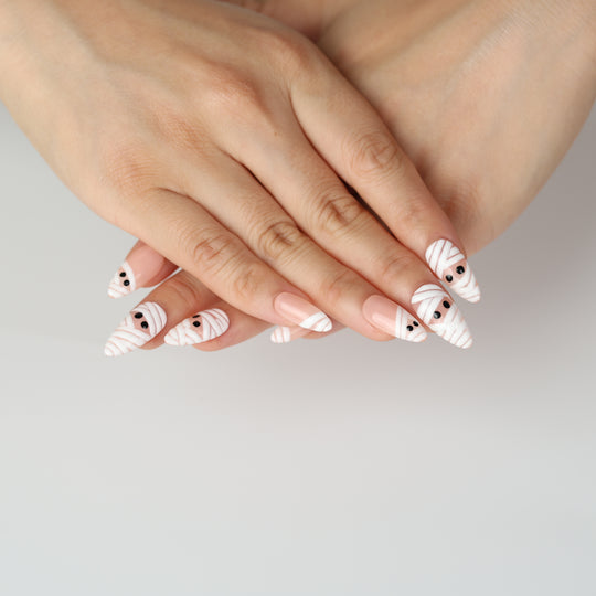 Peekaboo Mummy press-on nails on hands with white bandage stripes and black eyes