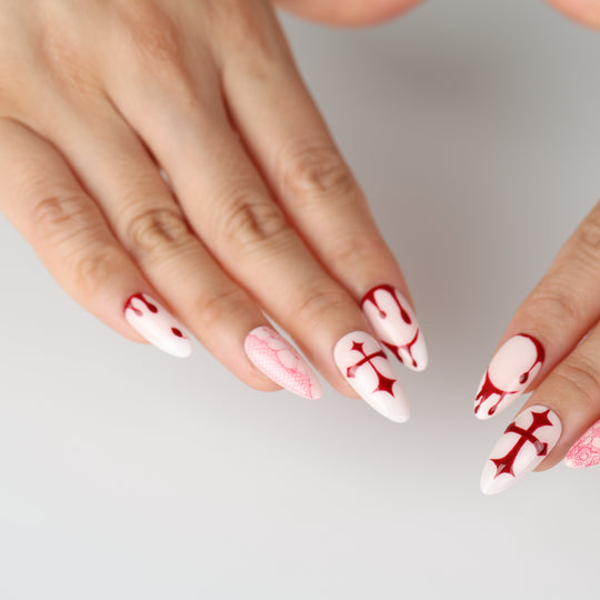 Blood Lace press-on nails on hand, blush base with red lace, crosses and blood-drip accents