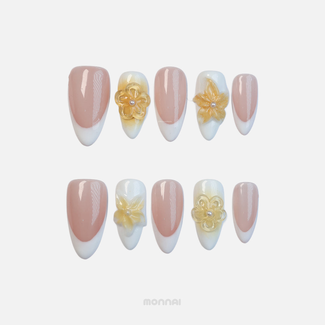 Medium almond press-on nails with a nude base, white French tips, and 3D yellow floral accents