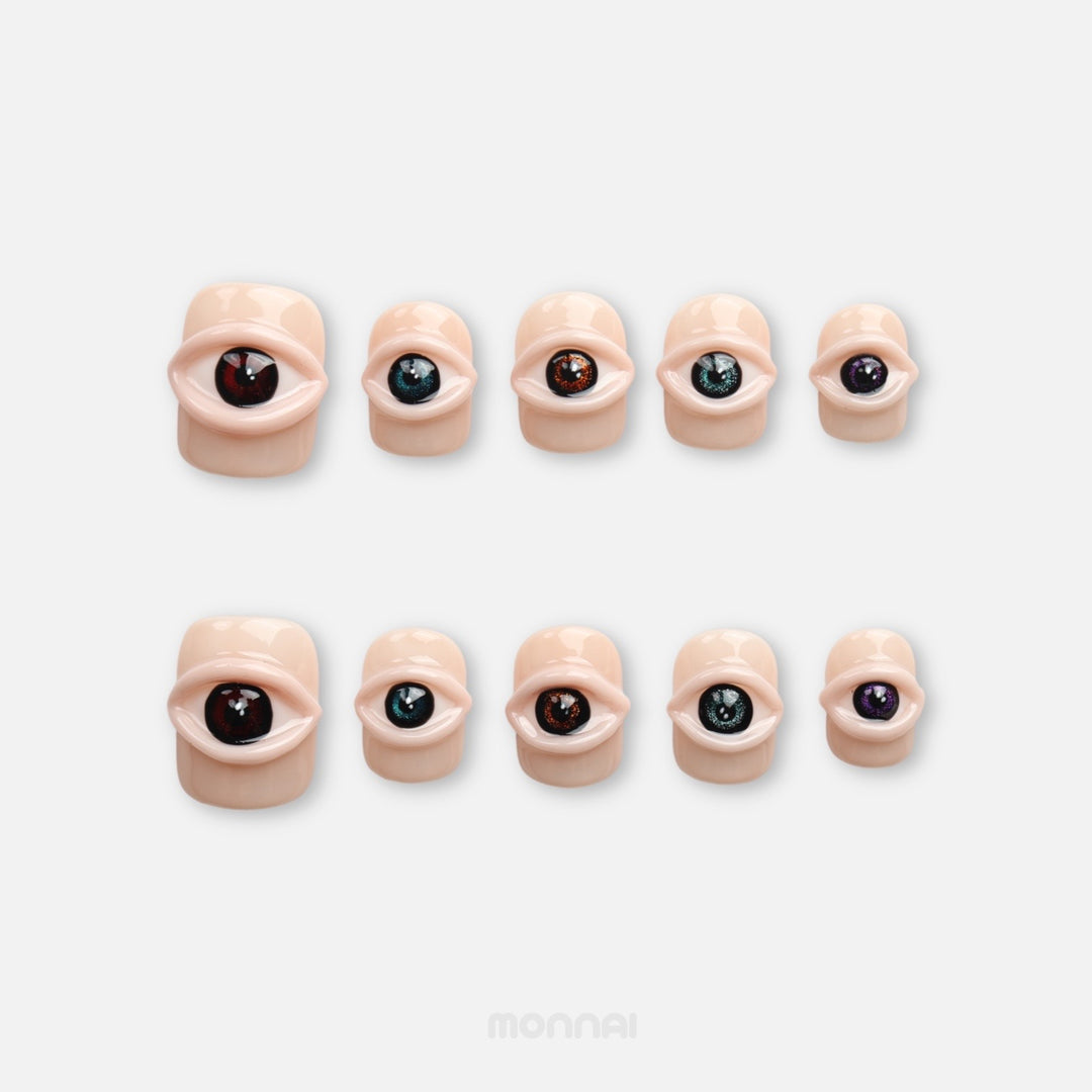 Spellbound Gaze press on nails with 3D eye details on a glossy peachy nude base
