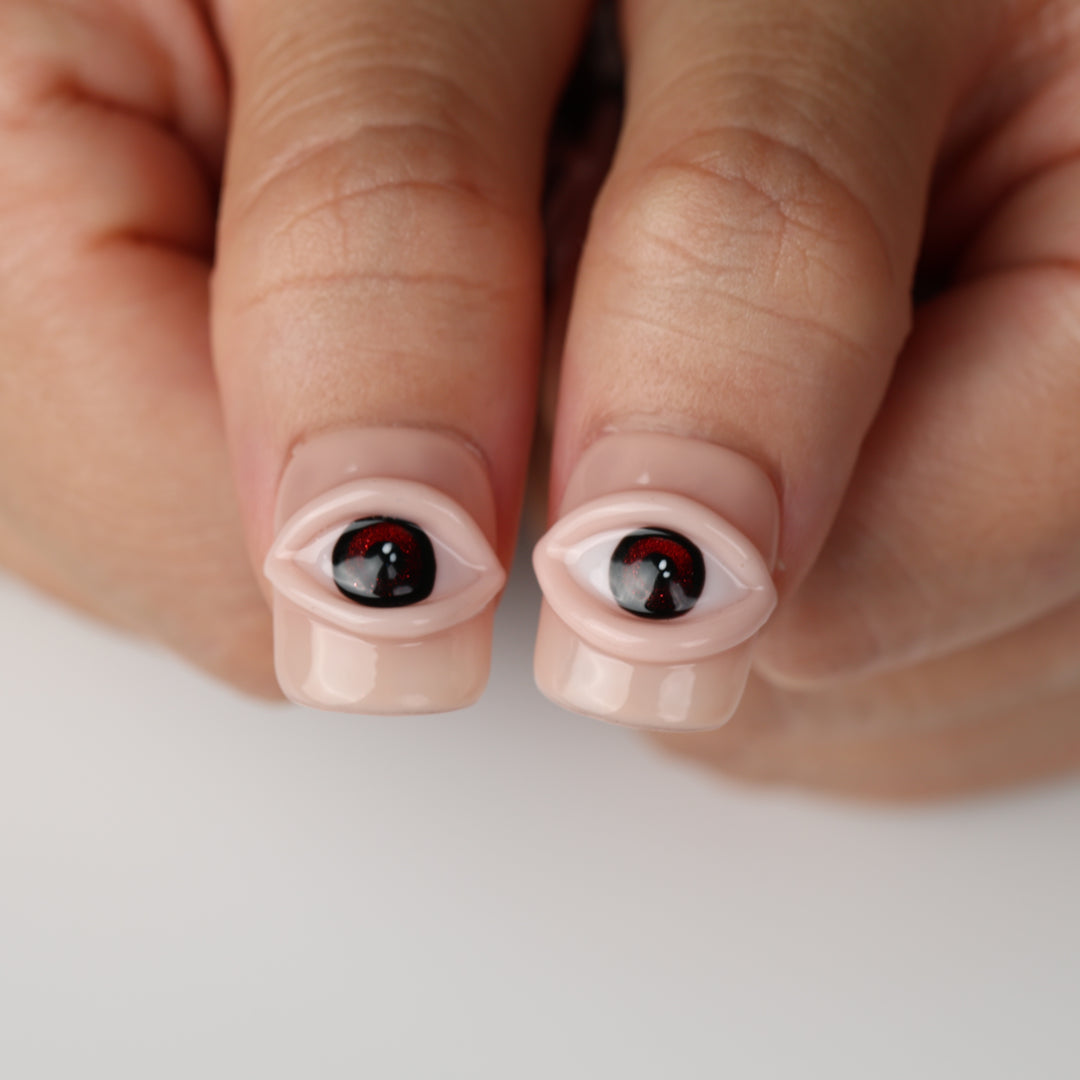 Spellbound Gaze press on nails with sculpted 3D eye design on glossy peachy nude base