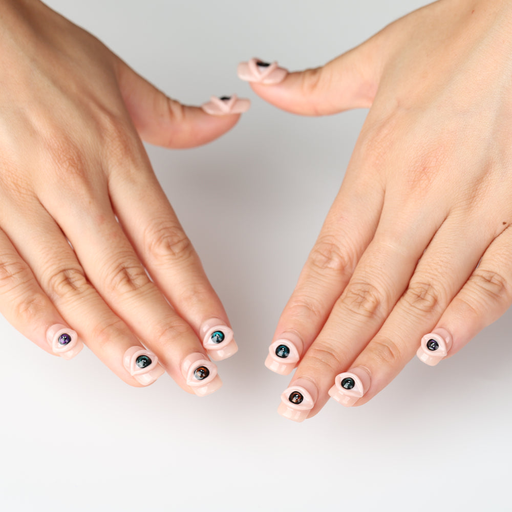 Spellbound Gaze press on nails with sculpted 3D eyes on glossy peachy nude base