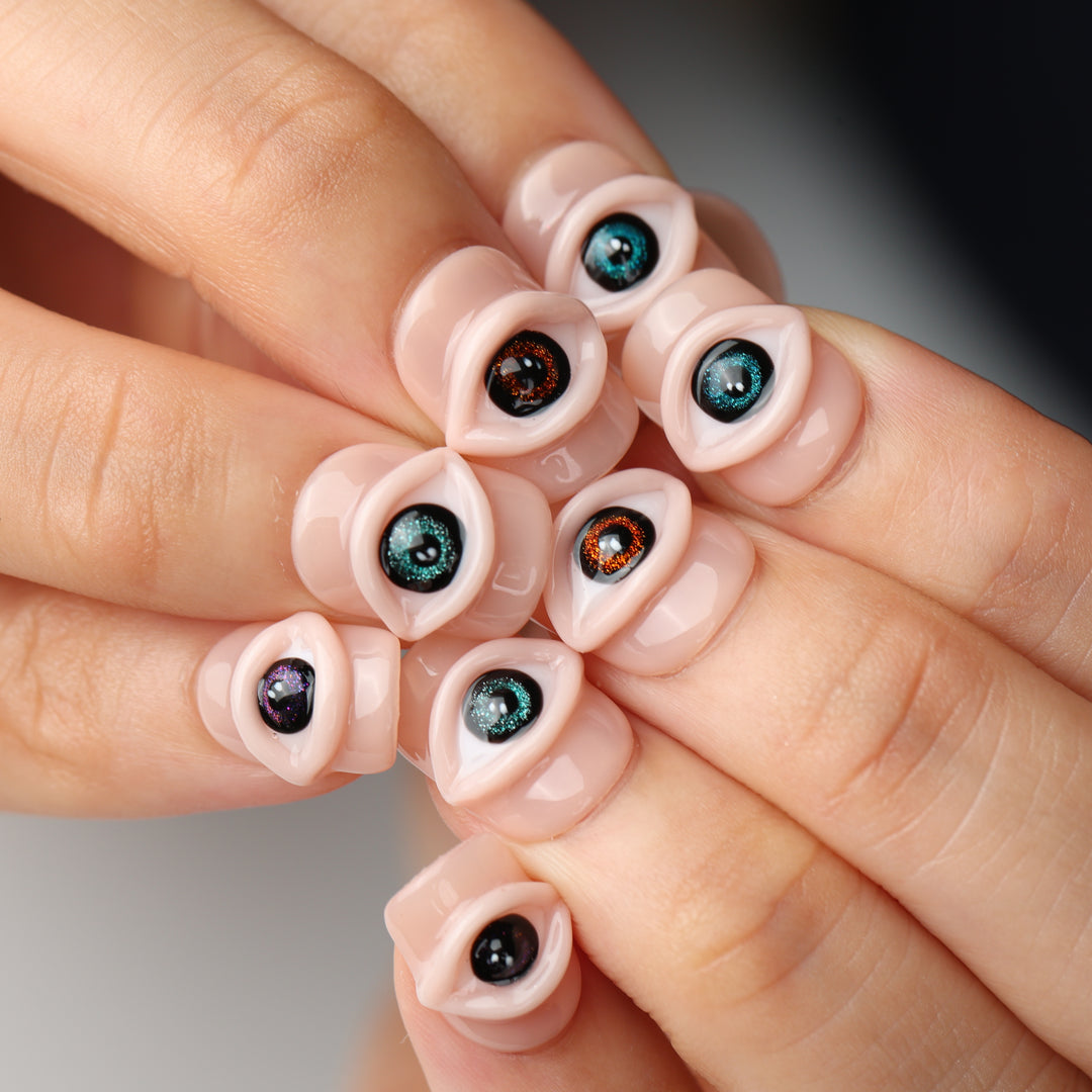 Spellbound Gaze press on nails with sculpted 3D eyes on glossy peachy nude base, surreal multicolor iris design